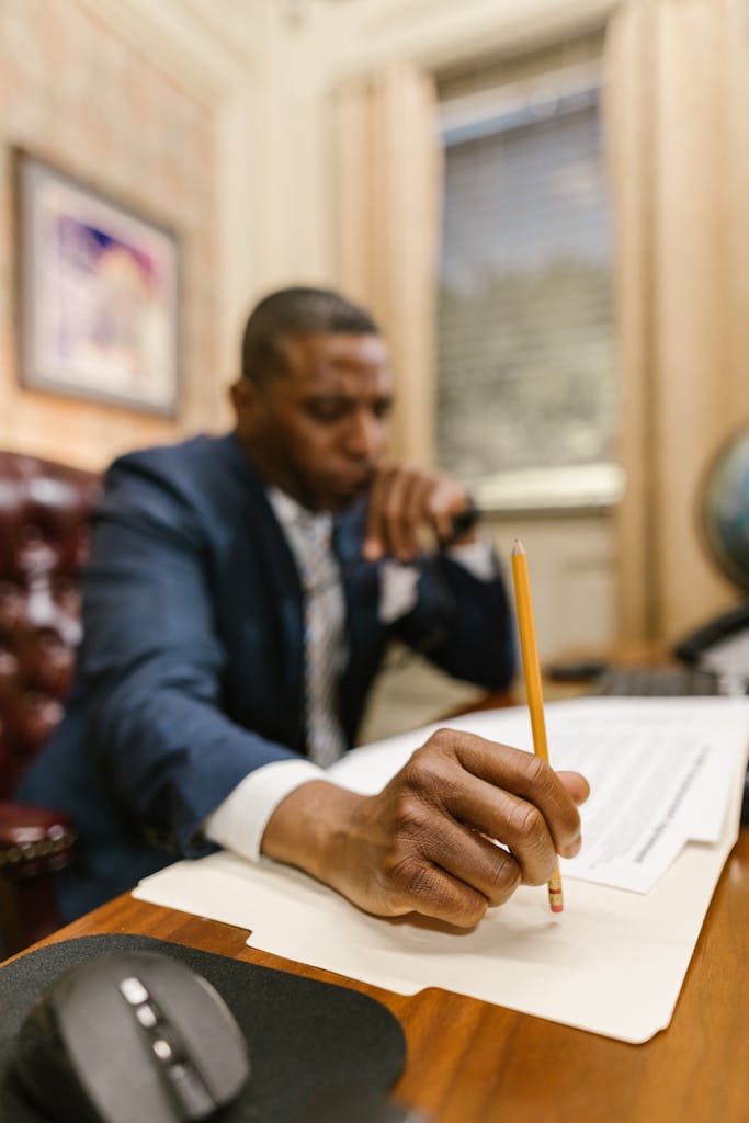 A professional lawyer writes notes while reviewing legal documents in an office.
